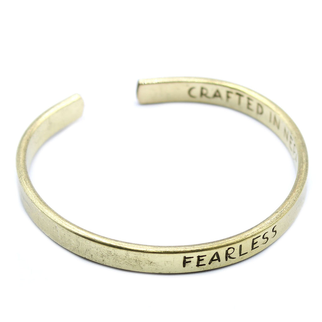 Gold bracelet with 'FEARLESS' engraved on a white background