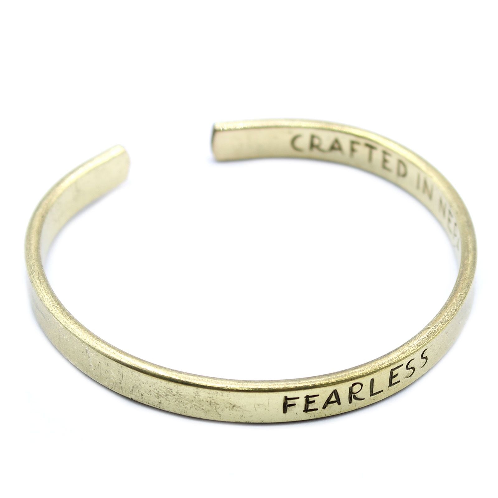 Gold bracelet with 'FEARLESS' engraved on a white background