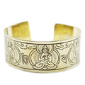 Gold bracelet with engraved designs on a white background